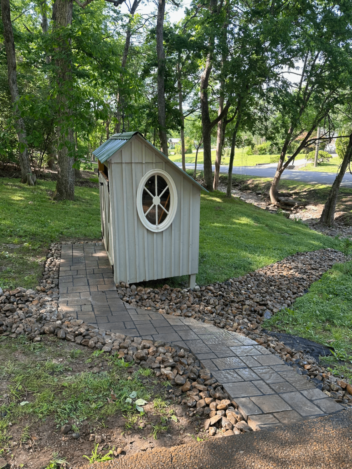 Paver walkway to garden shed flanked by river-rock dry creek beds for yard drainage, Tennessee
