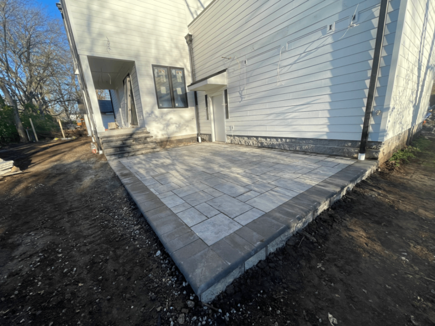 New paver patio with charcoal soldier-course border at rear entry of modern home, Tennessee