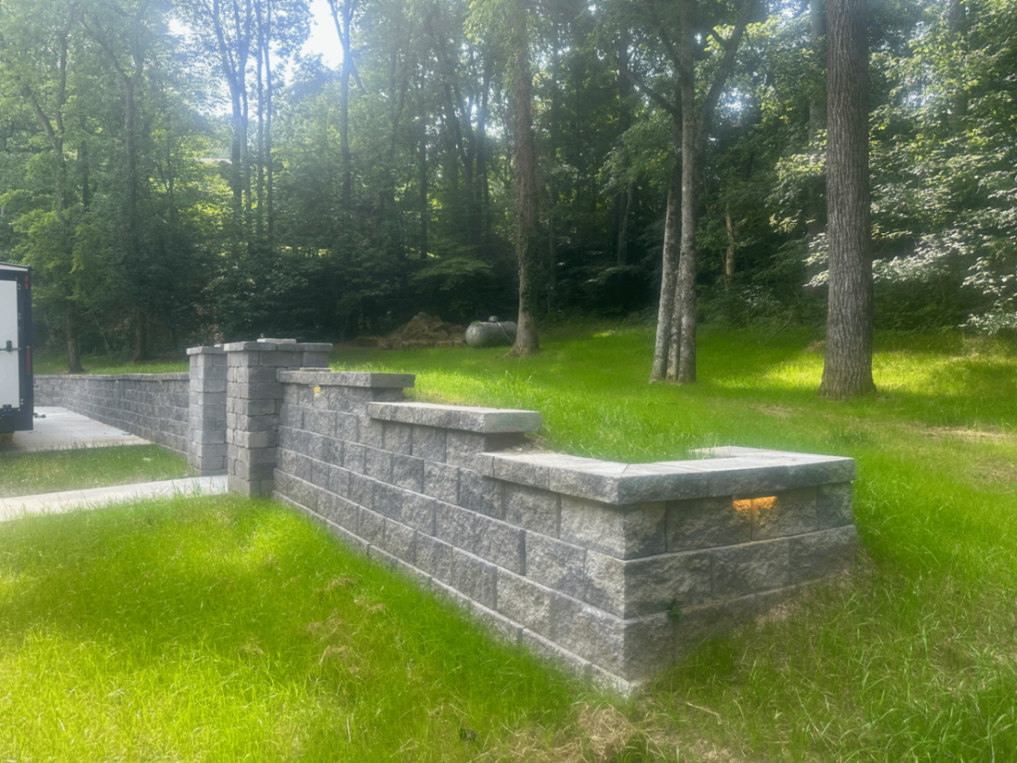 Retaining wall corner detail with capstones and built-in wall lighting on wooded homesite, Tennessee
