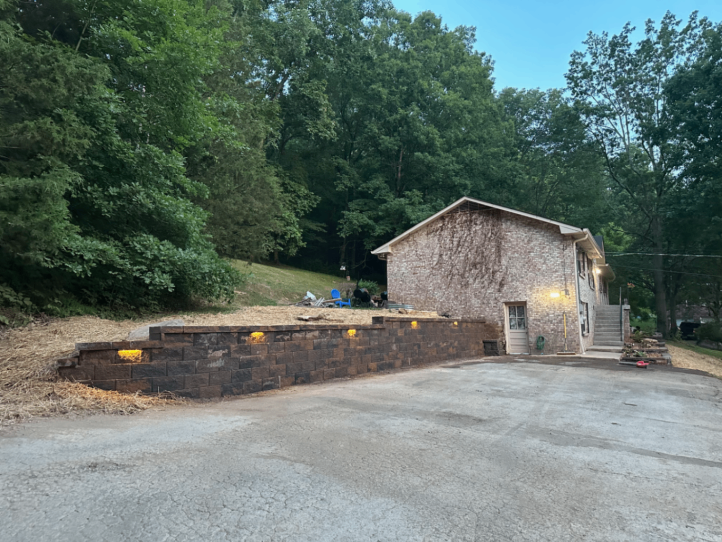 Drive approach retaining wall with integrated landscape lighting on wooded property, Tennessee
